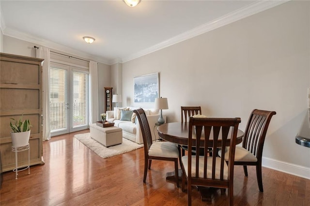 dining space featuring ornamental molding, wood finished floors, and baseboards