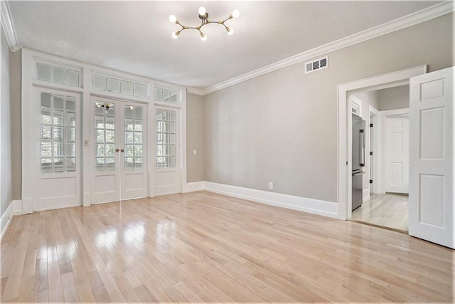 empty room with ornamental molding, light wood-type flooring, and french doors