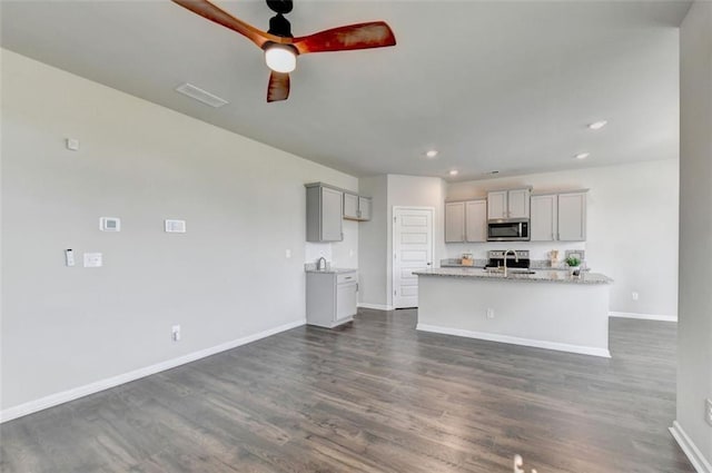 kitchen with dark wood finished floors, stainless steel microwave, baseboards, and gray cabinetry