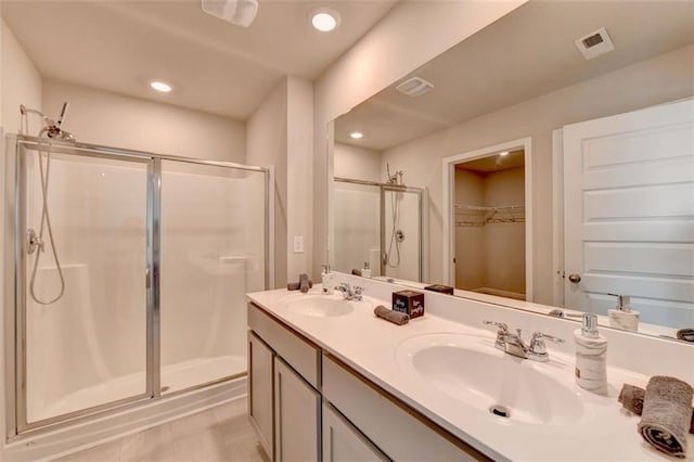 full bath with double vanity, visible vents, a shower stall, and a sink