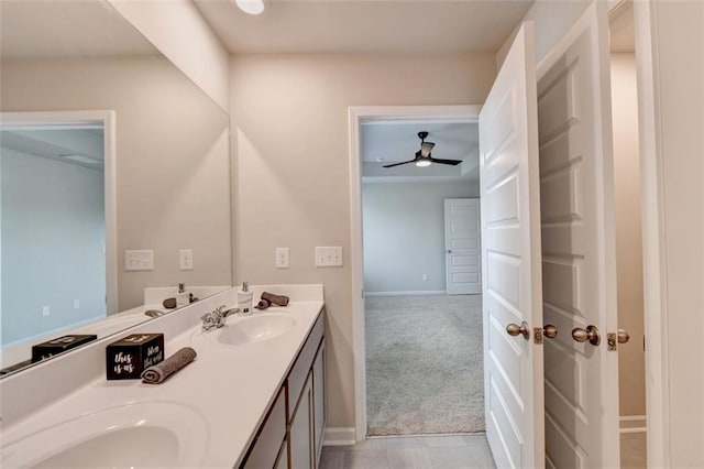 full bath featuring double vanity, baseboards, a ceiling fan, and a sink