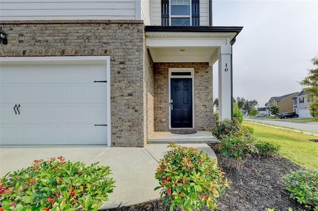 doorway to property featuring a garage and brick siding