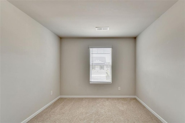 spare room featuring light carpet, visible vents, and baseboards