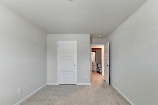 unfurnished bedroom featuring light colored carpet and baseboards