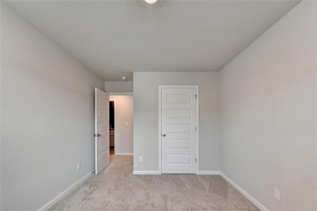 unfurnished bedroom with light colored carpet and baseboards