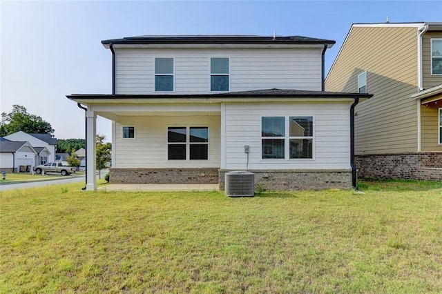 rear view of property with central air condition unit, a lawn, and brick siding