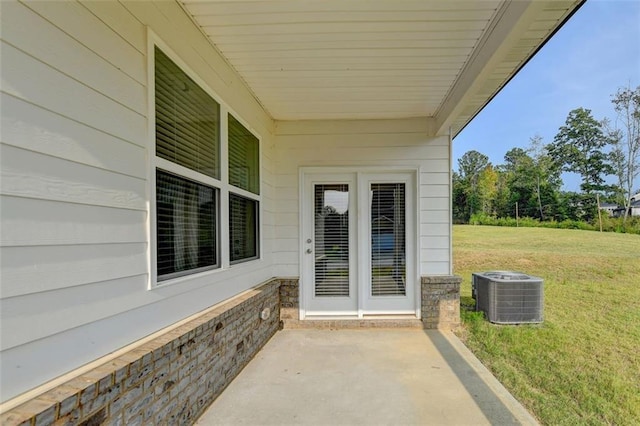 view of exterior entry featuring central AC unit, a patio, and a yard