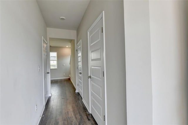 corridor featuring baseboards and dark wood-style flooring