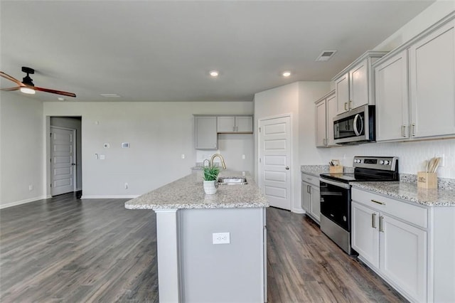 kitchen featuring a sink, stainless steel appliances, a center island with sink, and dark wood-style flooring