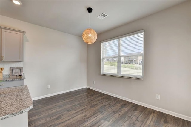 unfurnished dining area featuring visible vents, baseboards, and dark wood-type flooring