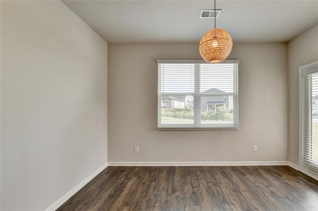 unfurnished room with a wealth of natural light, visible vents, baseboards, and dark wood-style flooring