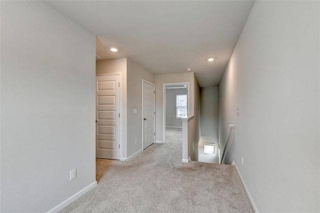 corridor featuring baseboards, an upstairs landing, and carpet