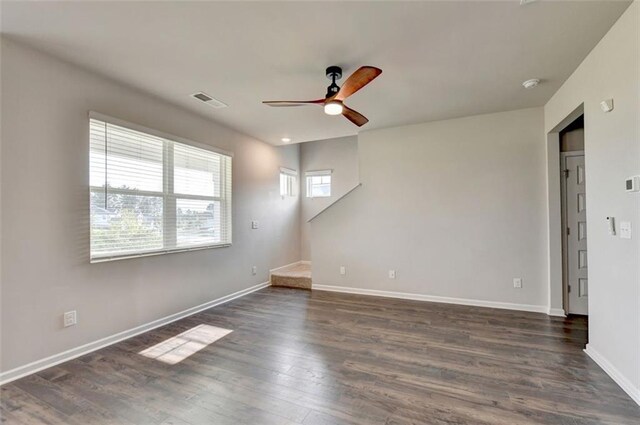 unfurnished room featuring stairway, a ceiling fan, baseboards, visible vents, and dark wood finished floors