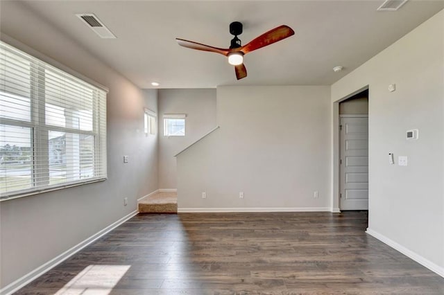 empty room with baseboards, visible vents, dark wood-style flooring, and ceiling fan