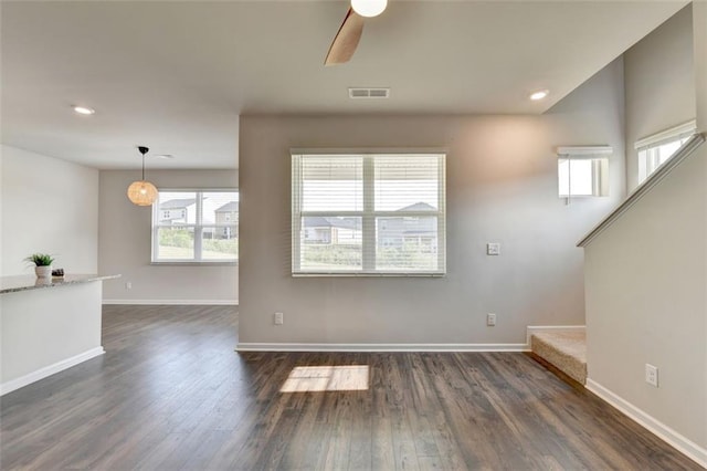 unfurnished living room featuring dark wood-style floors, visible vents, and baseboards