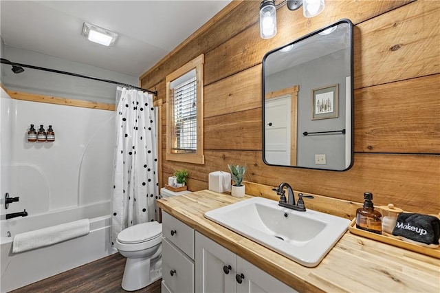 full bathroom with wood walls, shower / bath combo with shower curtain, toilet, vanity, and hardwood / wood-style floors