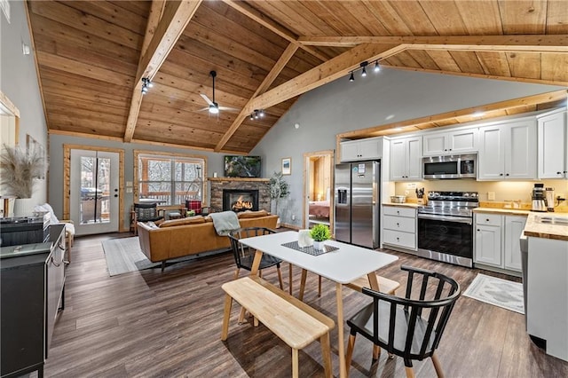 kitchen featuring white cabinetry, dark hardwood / wood-style floors, stainless steel appliances, wooden ceiling, and a fireplace