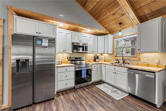 kitchen featuring appliances with stainless steel finishes, butcher block counters, white cabinets, pendant lighting, and sink