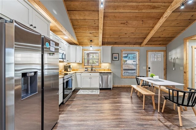 kitchen with sink, lofted ceiling with beams, appliances with stainless steel finishes, white cabinets, and pendant lighting