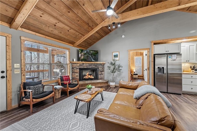 living room featuring beamed ceiling, dark hardwood / wood-style flooring, wooden ceiling, and a stone fireplace