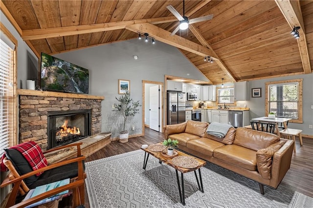 living room featuring hardwood / wood-style flooring, beamed ceiling, wooden ceiling, and a stone fireplace