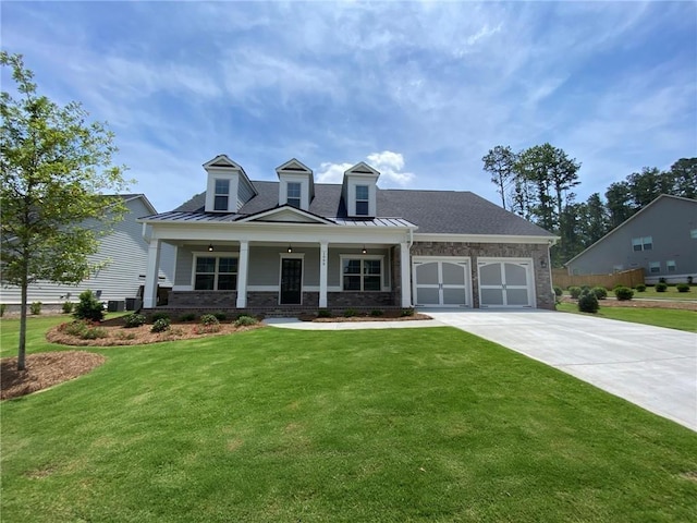 view of front of home with covered porch, a front yard, and a garage