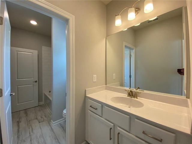 bathroom with toilet, vanity, and hardwood / wood-style floors