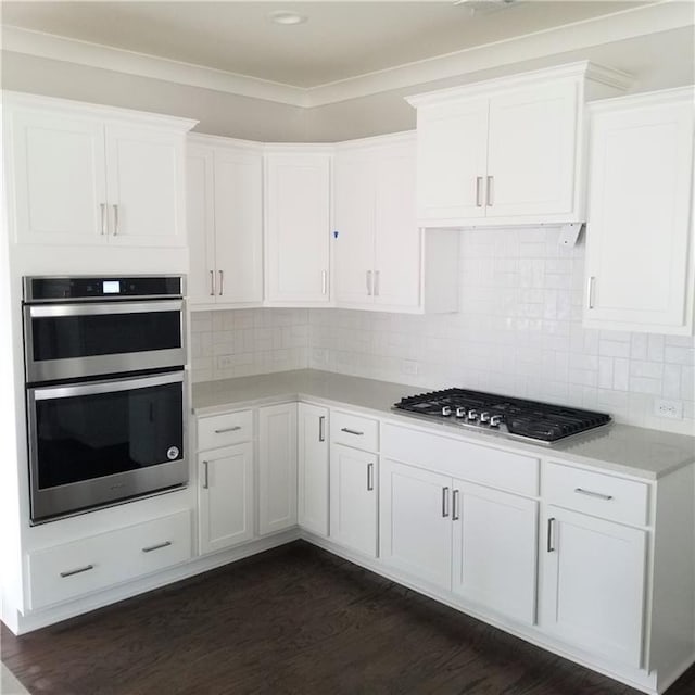 kitchen featuring white cabinets, backsplash, appliances with stainless steel finishes, and dark hardwood / wood-style floors