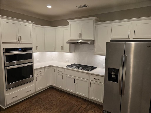 kitchen with white cabinets, appliances with stainless steel finishes, dark hardwood / wood-style flooring, and tasteful backsplash