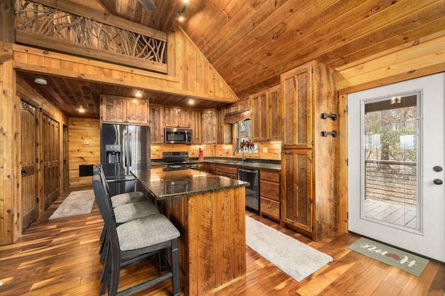 kitchen with a kitchen island, dark wood finished floors, stainless steel appliances, wooden ceiling, and wood walls