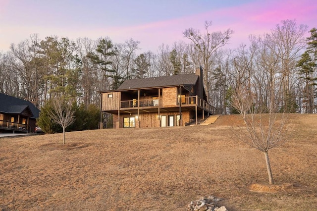 back of property at dusk with a deck and a chimney