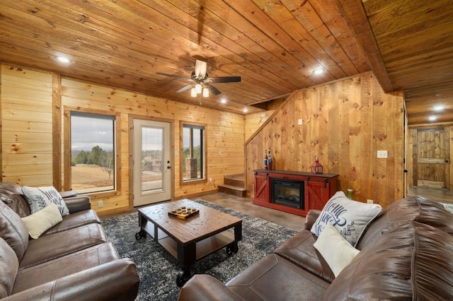 living area with a ceiling fan, a glass covered fireplace, recessed lighting, wooden walls, and wooden ceiling