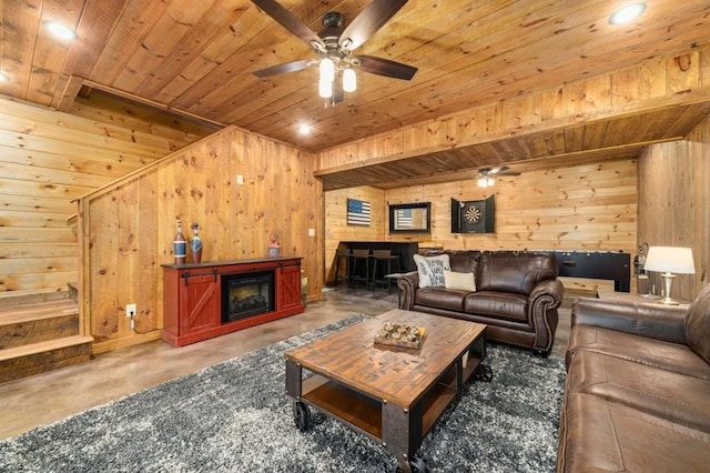 living area featuring a ceiling fan, wooden ceiling, a fireplace, and wood walls