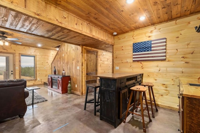 bar featuring a ceiling fan, finished concrete flooring, wooden walls, and wood ceiling