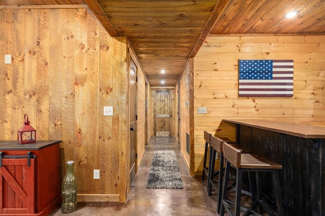 corridor with concrete floors, wooden walls, and wood ceiling