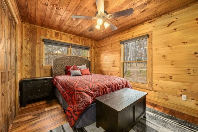 bedroom with a ceiling fan, wooden ceiling, wooden walls, and wood finished floors