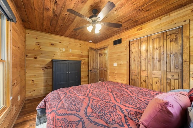 bedroom with visible vents, wood finished floors, wood walls, and wooden ceiling