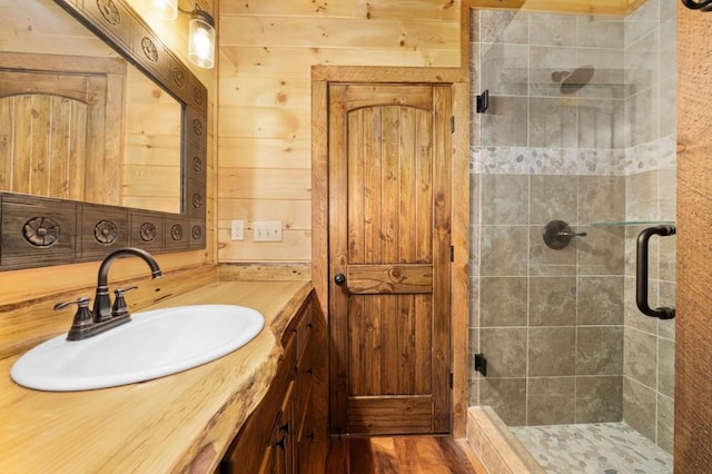 bathroom featuring a stall shower, vanity, and wood walls