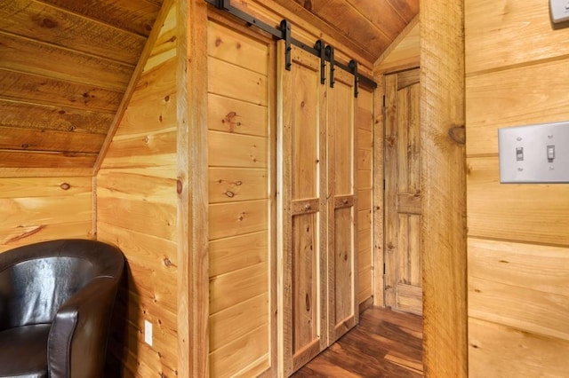 corridor featuring wood finished floors, lofted ceiling, wood ceiling, wood walls, and a barn door