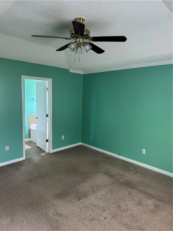 spare room with carpet floors, a textured ceiling, baseboards, and ceiling fan