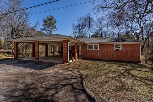 view of front of home featuring an attached carport, brick siding, and driveway