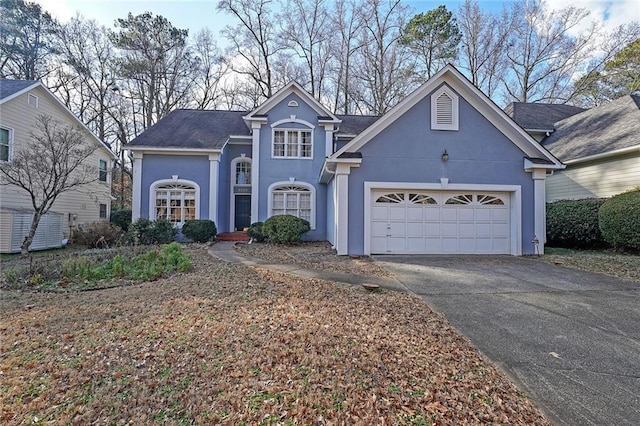 traditional-style home with an attached garage, driveway, and stucco siding