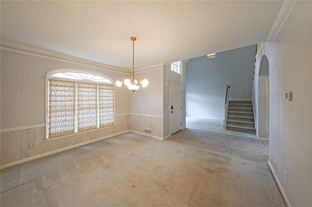 unfurnished dining area featuring a chandelier, a wainscoted wall, carpet floors, stairway, and crown molding