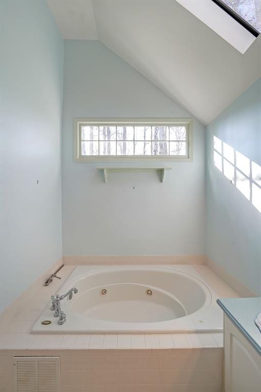 full bath featuring lofted ceiling, plenty of natural light, a whirlpool tub, and visible vents