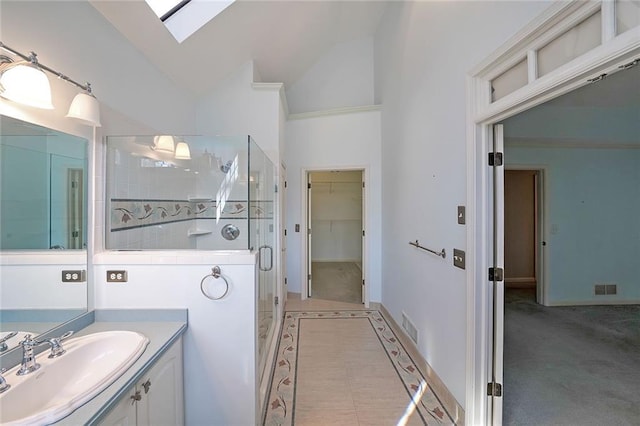 bathroom featuring vaulted ceiling with skylight, visible vents, a shower stall, and a spacious closet