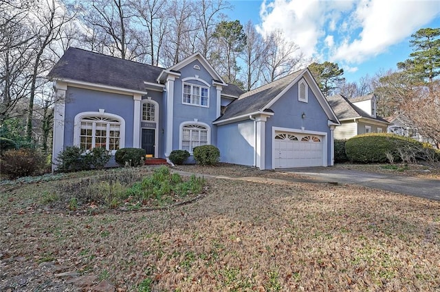 traditional home featuring driveway, a garage, and stucco siding