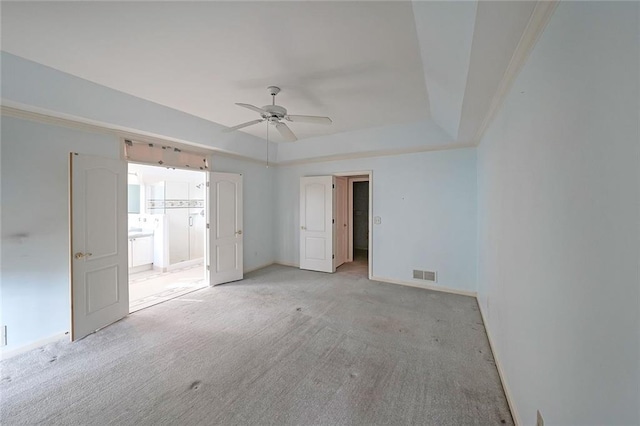 unfurnished room featuring ceiling fan, light carpet, visible vents, baseboards, and a tray ceiling