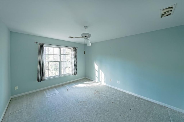 carpeted spare room with ceiling fan, visible vents, and baseboards