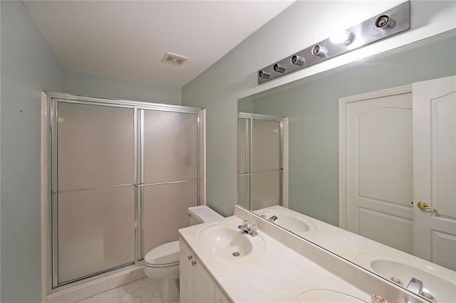 bathroom featuring double vanity, visible vents, toilet, a sink, and a shower stall