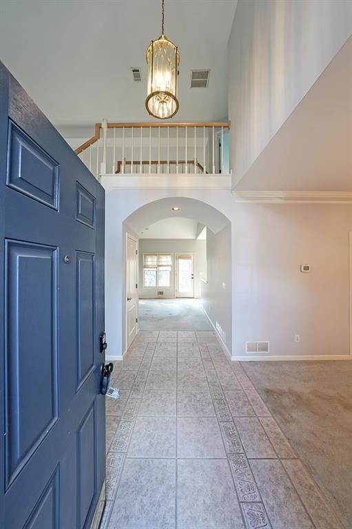 entrance foyer with arched walkways, a towering ceiling, and visible vents